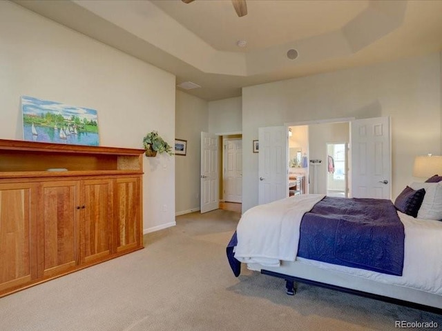 bedroom with light carpet, baseboards, a ceiling fan, a towering ceiling, and a tray ceiling