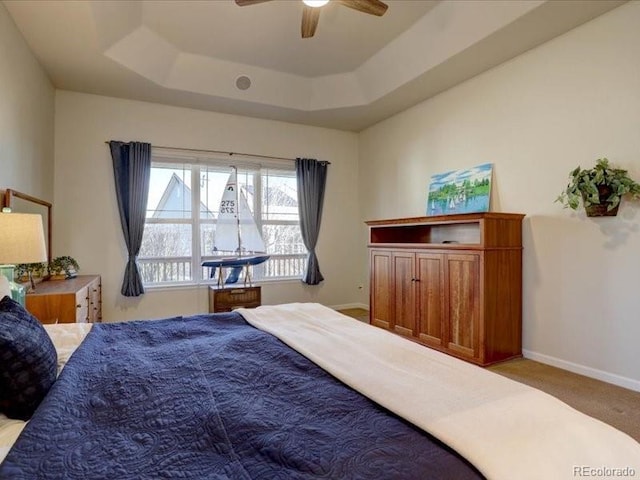 bedroom featuring baseboards, a tray ceiling, ceiling fan, and carpet flooring