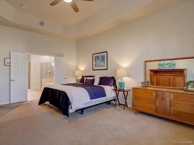 bedroom featuring a tray ceiling, light carpet, connected bathroom, and a high ceiling