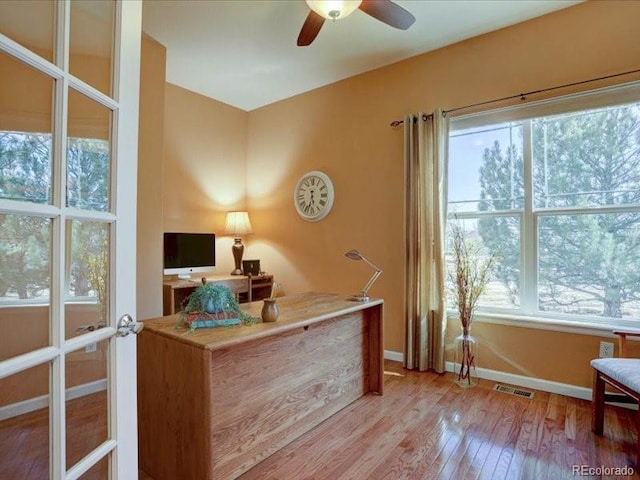 home office with a ceiling fan, light wood-style flooring, visible vents, and baseboards