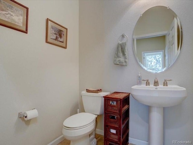 bathroom with baseboards, a sink, and toilet