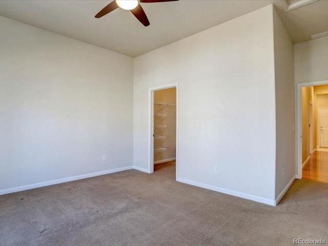 carpeted empty room with a ceiling fan and baseboards