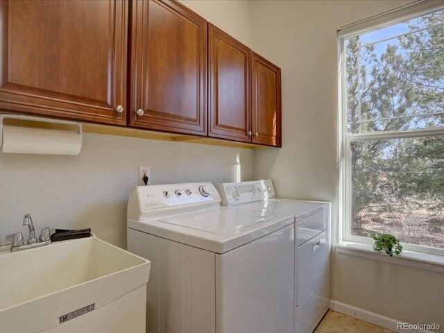 laundry room featuring a wealth of natural light, cabinet space, a sink, and separate washer and dryer