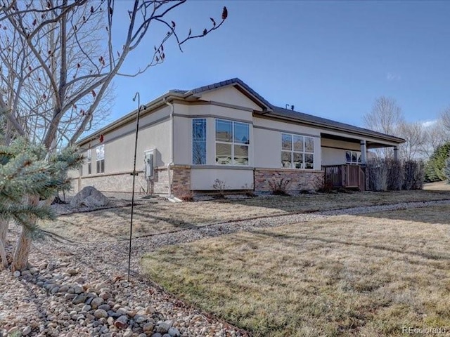 view of property exterior featuring stone siding, a lawn, and stucco siding