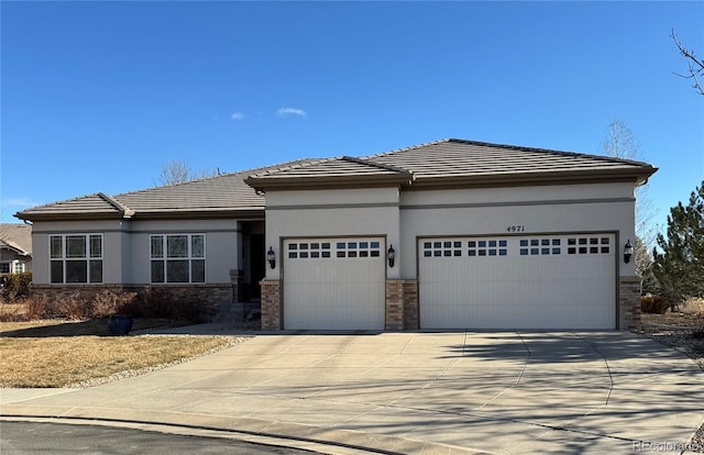 prairie-style house with a garage, concrete driveway, a tile roof, and stucco siding