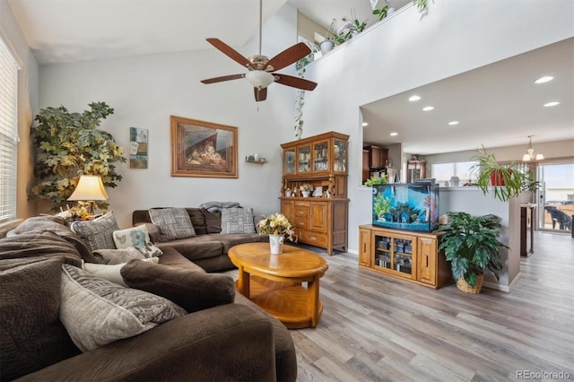 living room with ceiling fan, light wood finished floors, a towering ceiling, and recessed lighting