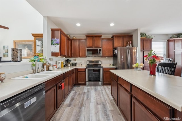 kitchen with stainless steel appliances, recessed lighting, light countertops, a sink, and light wood-type flooring