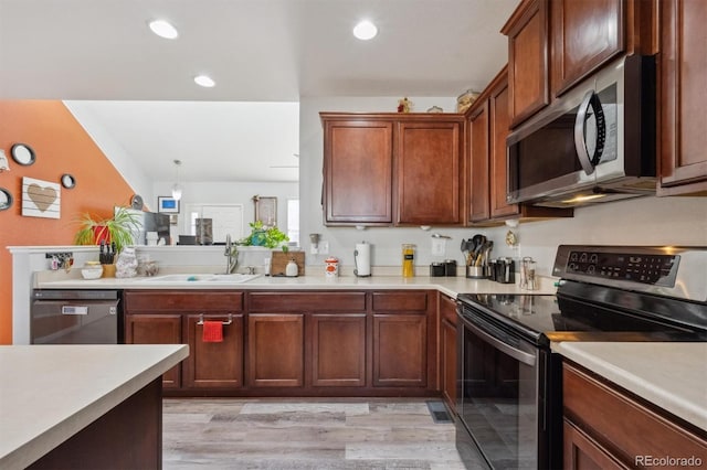 kitchen with appliances with stainless steel finishes, light countertops, light wood-type flooring, a sink, and recessed lighting