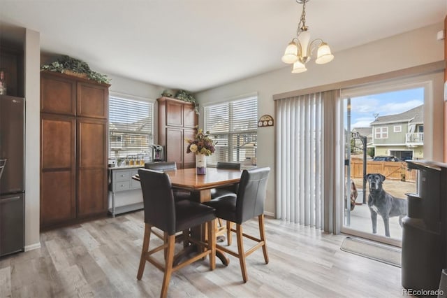 dining area featuring light wood-type flooring, baseboards, and an inviting chandelier