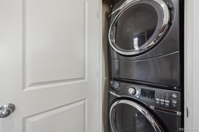 clothes washing area featuring stacked washer and clothes dryer and laundry area