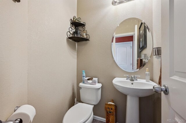 half bathroom featuring toilet and a sink