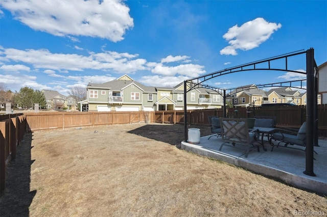 view of yard featuring a fenced backyard, a residential view, and a patio