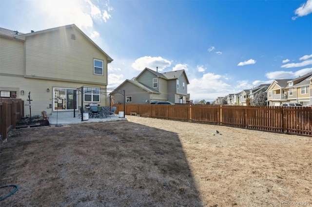 view of yard featuring a patio area, a fenced backyard, and a residential view