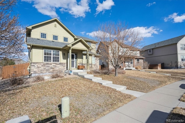 view of front facade featuring stone siding and fence