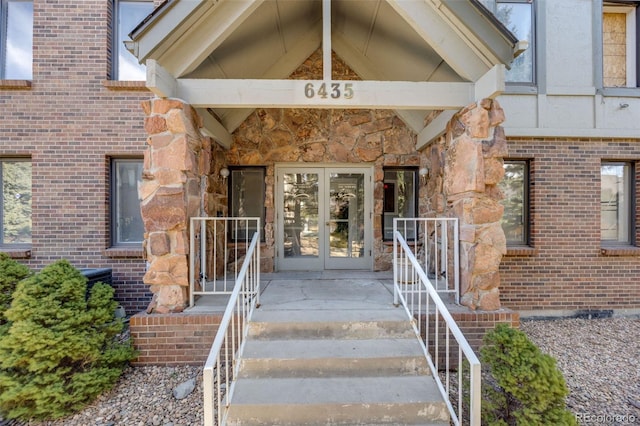 property entrance with brick siding, stone siding, and french doors