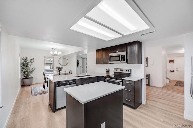 6435 S Dayton St Unit 103, Englewood, CO 80111 - kitchen featuring a peninsula, a sink, dark brown cabinets, a chandelier, and appliances with stainless steel finishes