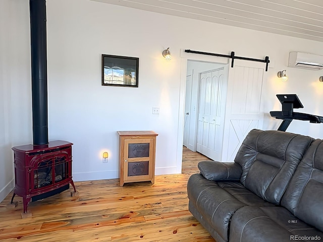 601 N Wood St, Silver Cliff, CO 81252 - living area with an AC wall unit, light wood-type flooring, a barn door, baseboards, and a wood stove