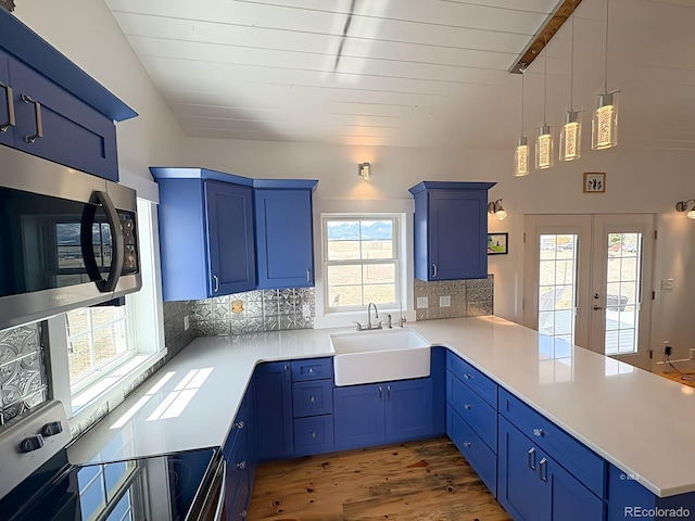 601 N Wood St, Silver Cliff, CO 81252 - kitchen featuring a sink, blue cabinetry, appliances with stainless steel finishes, a peninsula, and wood finished floors