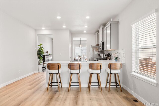 kitchen featuring appliances with stainless steel finishes, a peninsula, light countertops, a sink, and recessed lighting