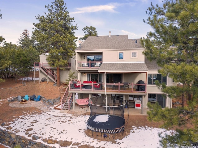 rear view of property with a balcony and a trampoline