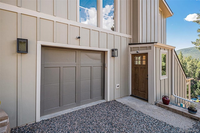 32783 Lodgepole Cir, Evergreen, CO 80439 - entrance to property featuring board and batten siding, a garage, driveway, and a mountain view