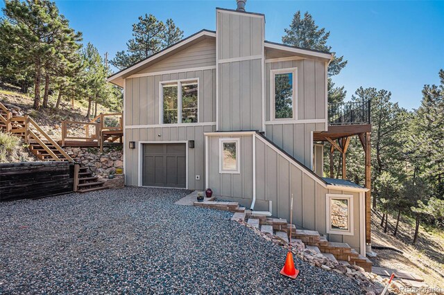 32783 Lodgepole Cir, Evergreen, CO 80439 - chalet / cabin with stairway, board and batten siding, a chimney, driveway, and a garage