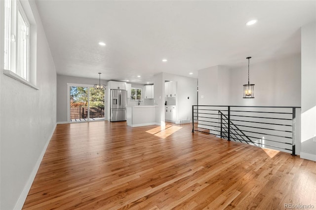 unfurnished living room with light hardwood / wood-style floors and an inviting chandelier