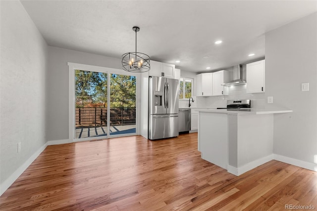 kitchen featuring wall chimney exhaust hood, white cabinets, stainless steel appliances, and light hardwood / wood-style floors