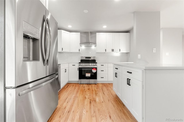 kitchen featuring white cabinetry, stainless steel appliances, and wall chimney exhaust hood