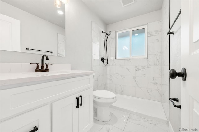 bathroom with vanity, toilet, and a tile shower