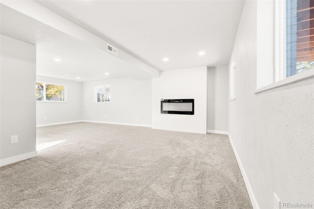 unfurnished living room featuring beam ceiling and carpet