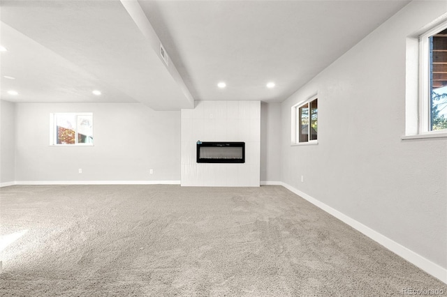 unfurnished living room featuring a fireplace, carpet flooring, and a healthy amount of sunlight