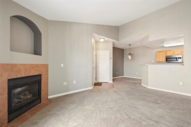 unfurnished living room with carpet, a fireplace, and baseboards