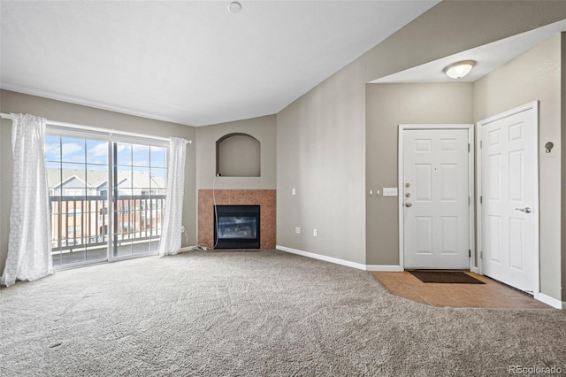 unfurnished living room with a tiled fireplace, carpet, and baseboards