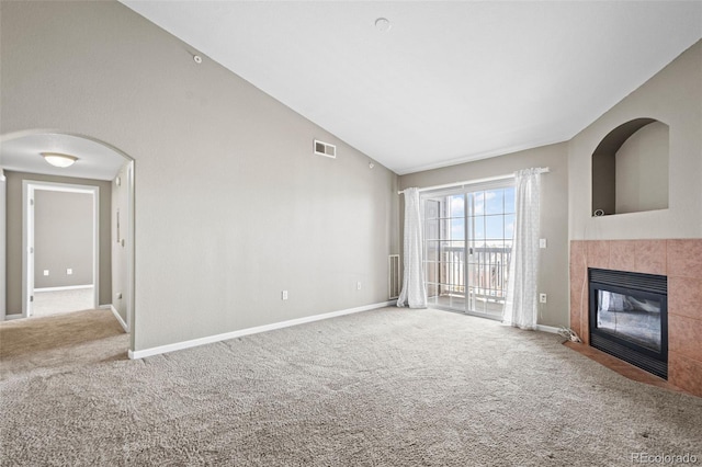 unfurnished living room with high vaulted ceiling, carpet flooring, visible vents, baseboards, and a tiled fireplace