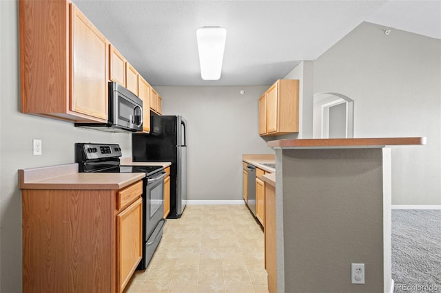 kitchen featuring stainless steel appliances, light countertops, light brown cabinetry, a peninsula, and baseboards