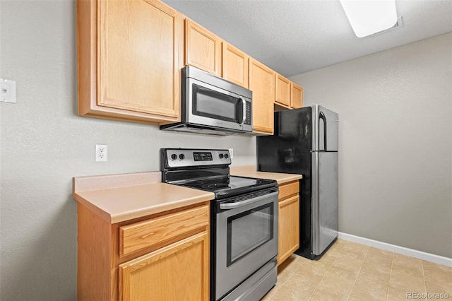 kitchen with baseboards, light brown cabinetry, stainless steel appliances, a textured ceiling, and light countertops