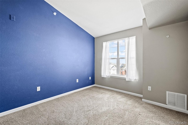 carpeted empty room featuring lofted ceiling, visible vents, and baseboards