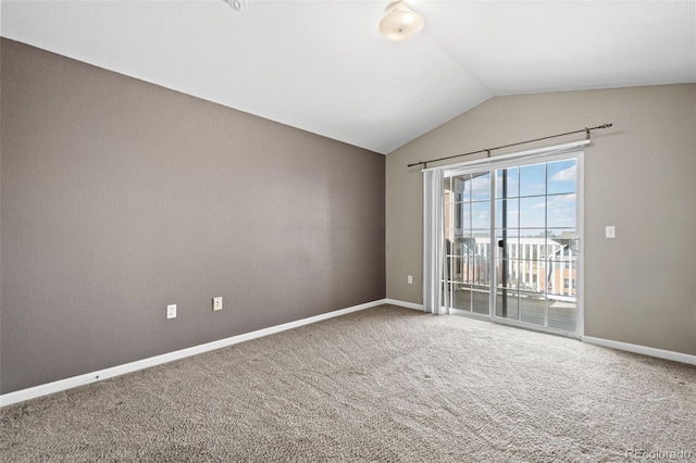 carpeted empty room featuring baseboards and vaulted ceiling