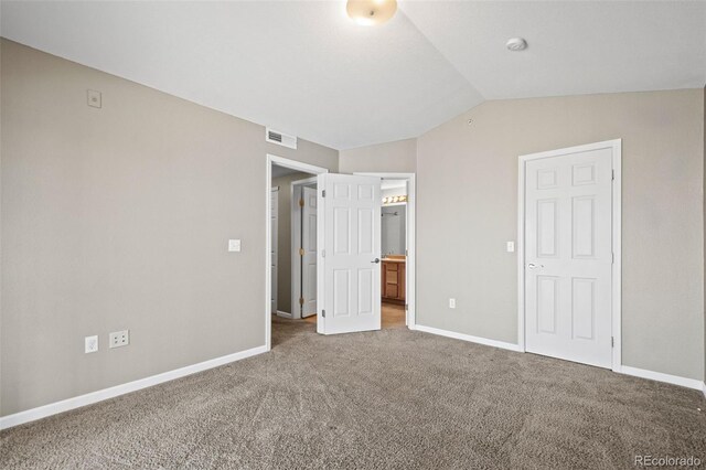 unfurnished bedroom with ensuite bathroom, carpet floors, visible vents, baseboards, and vaulted ceiling