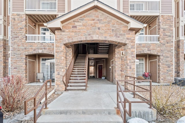 doorway to property with stone siding and central AC unit