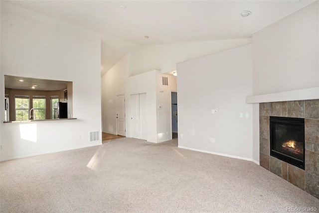 unfurnished living room featuring a tile fireplace, lofted ceiling, and carpet floors