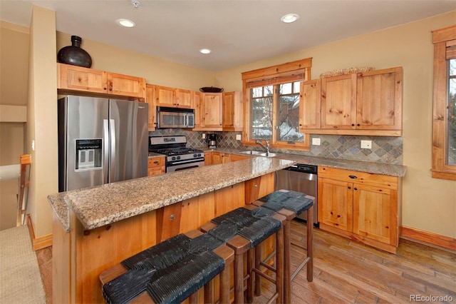 kitchen with light wood-type flooring, tasteful backsplash, stainless steel appliances, and a sink