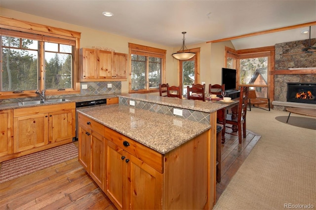 kitchen featuring a center island, a fireplace, decorative backsplash, stainless steel dishwasher, and a sink