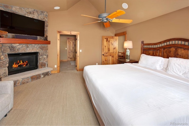 bedroom with carpet floors, vaulted ceiling, a stone fireplace, ceiling fan, and baseboards