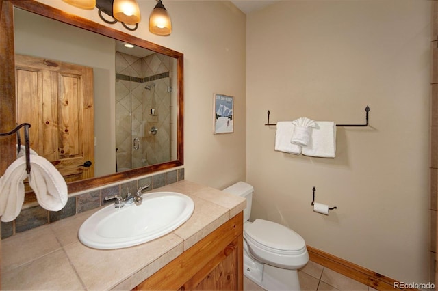 bathroom featuring a stall shower, baseboards, toilet, tile patterned flooring, and vanity