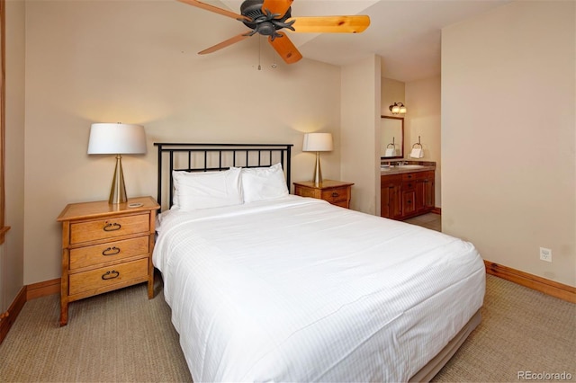 bedroom with light carpet, ensuite bath, and baseboards