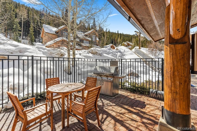 snow covered deck featuring grilling area and a view of trees