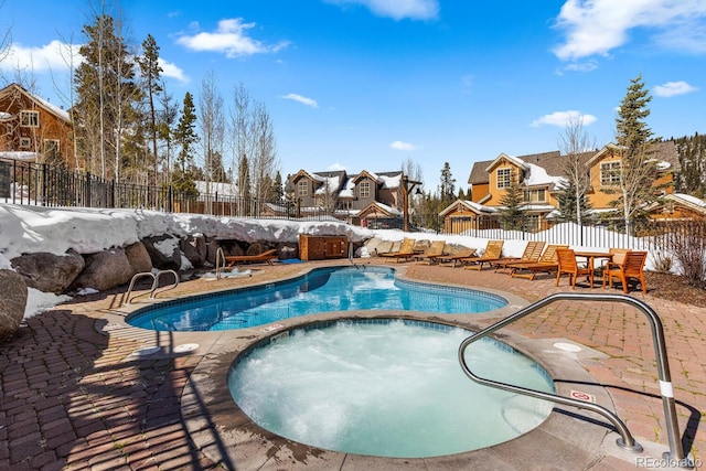 pool with an in ground hot tub, a patio area, a fenced backyard, and a residential view