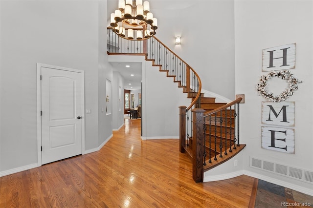 entryway with wood-type flooring, a chandelier, and a high ceiling